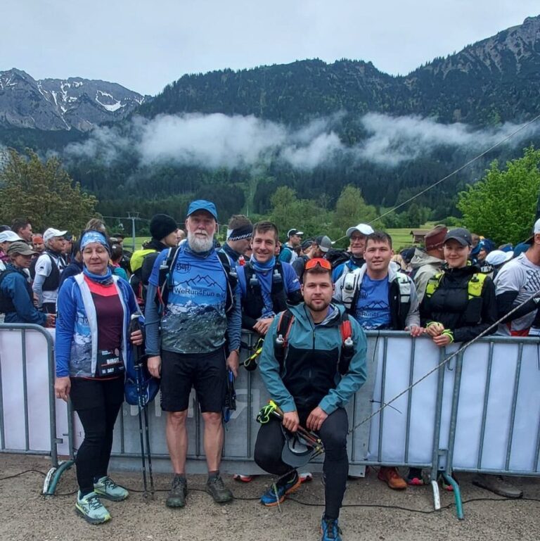 Gruppe von Trailrunnern vor den bayerischen Alpen, bereit für das Mountain Running Abenteuer - We Run 4 Fun!