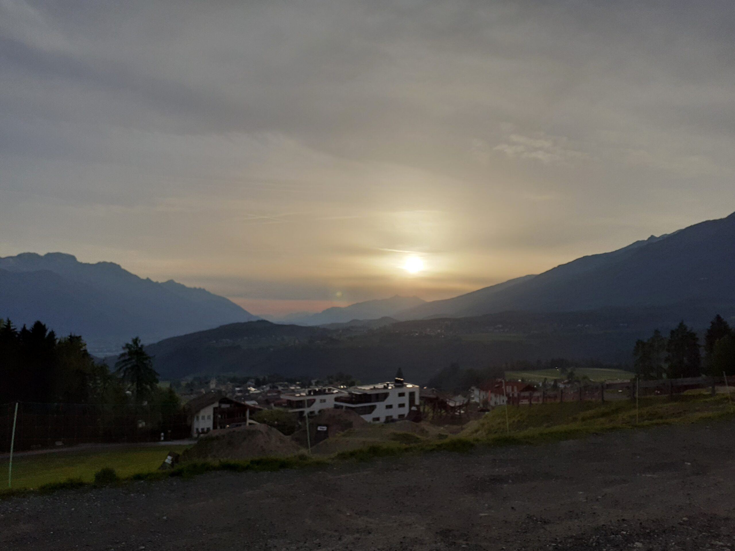 Sonnenuntergang über Bergpanorama mit Dorf und Bergen im Hintergrund. - We Run 4 Fun!