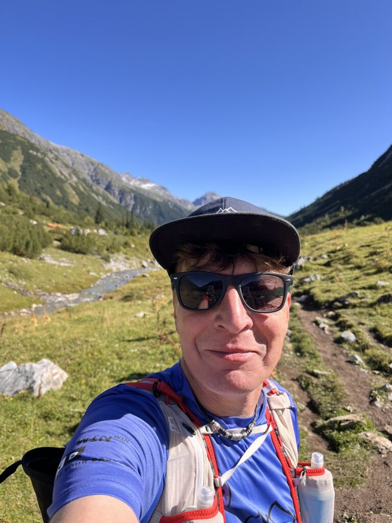 Läufer macht Selfie beim Transalpine Run 2025 in den Bergen. - We Run 4 Fun!