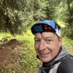 Läufer im Wald beim Transalpine Run 2025, mit Mütze und Rucksack. - We Run 4 Fun!