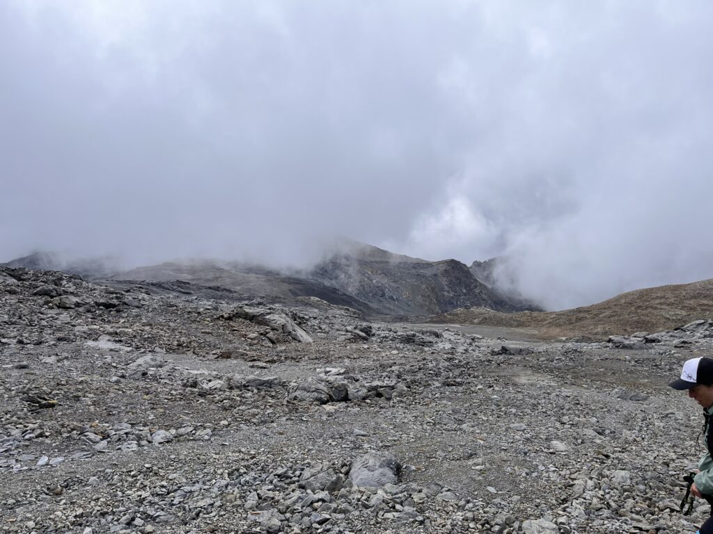 Transalpine Run 2025: raue Berglandschaft mit Nebel und Wanderer - We Run 4 Fun!
