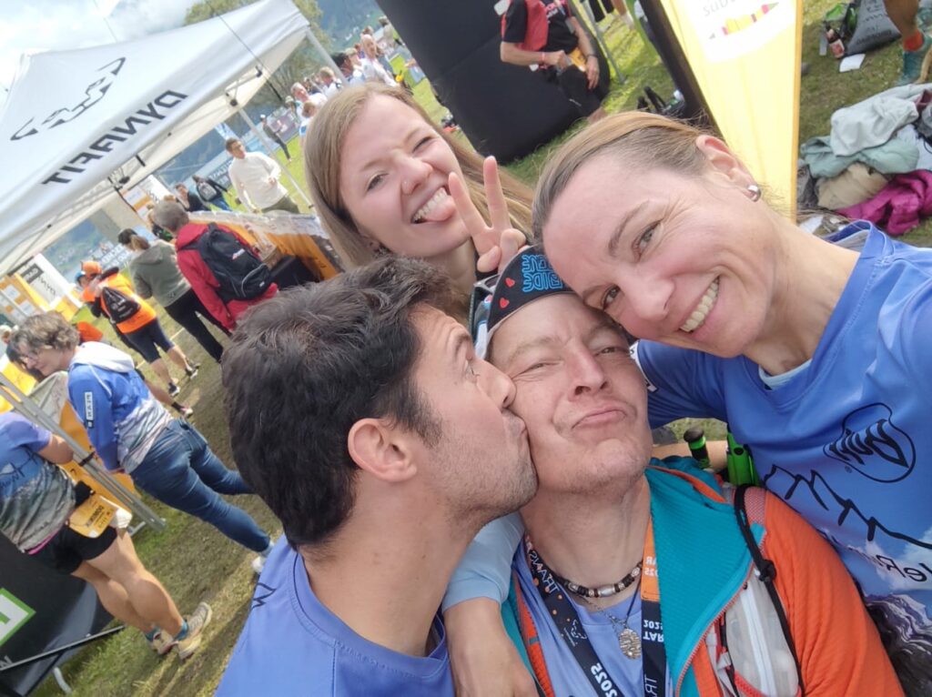 Freunde feiern beim Transalpine Run 2025 einen Läufer mit Küssen und Victory-Zeichen. - We Run 4 Fun!