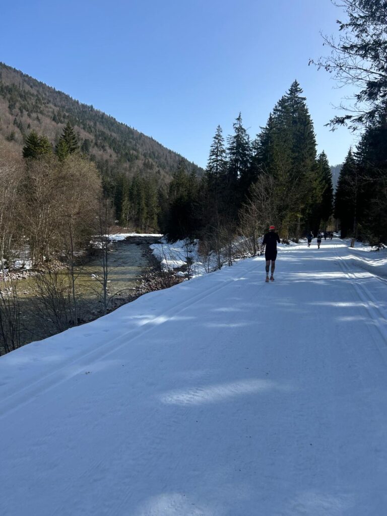 Läufer auf verschneitem Weg am Fluss in Reit i. Winkel beim Mountainman Winter Trail. - We Run 4 Fun!