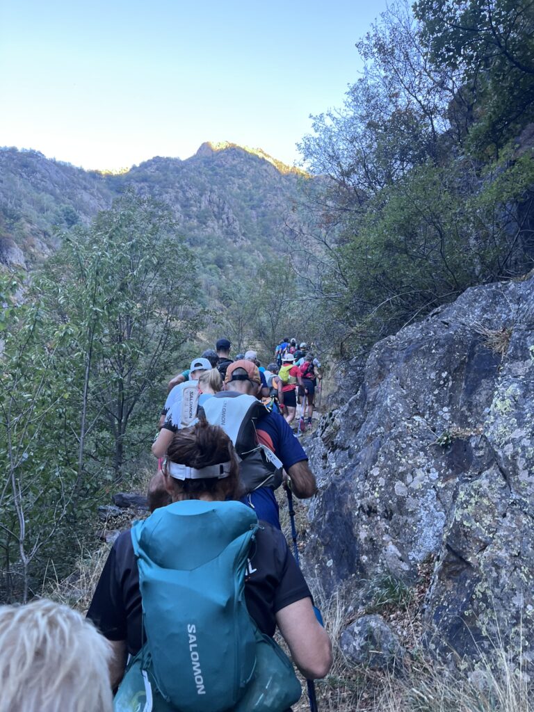 Läufergruppe wandert auf felsigem Bergpfad im Sonnenlicht - We Run 4 Fun!